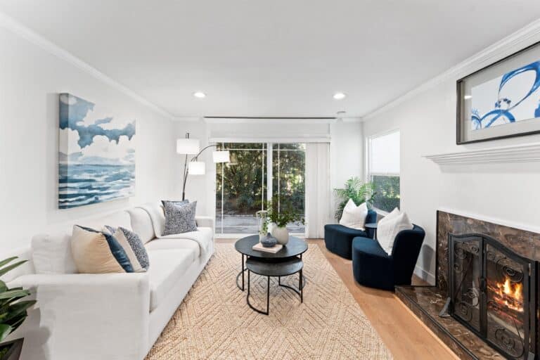 A bright living room with elegant white furniture and a stylish fireplace, enhancing the space's comfort.