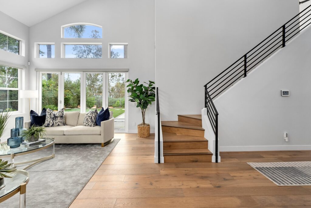A well-furnished living room with a staircase leading to an upper level and a stylish couch for seating, Home Staging Service Near Me
