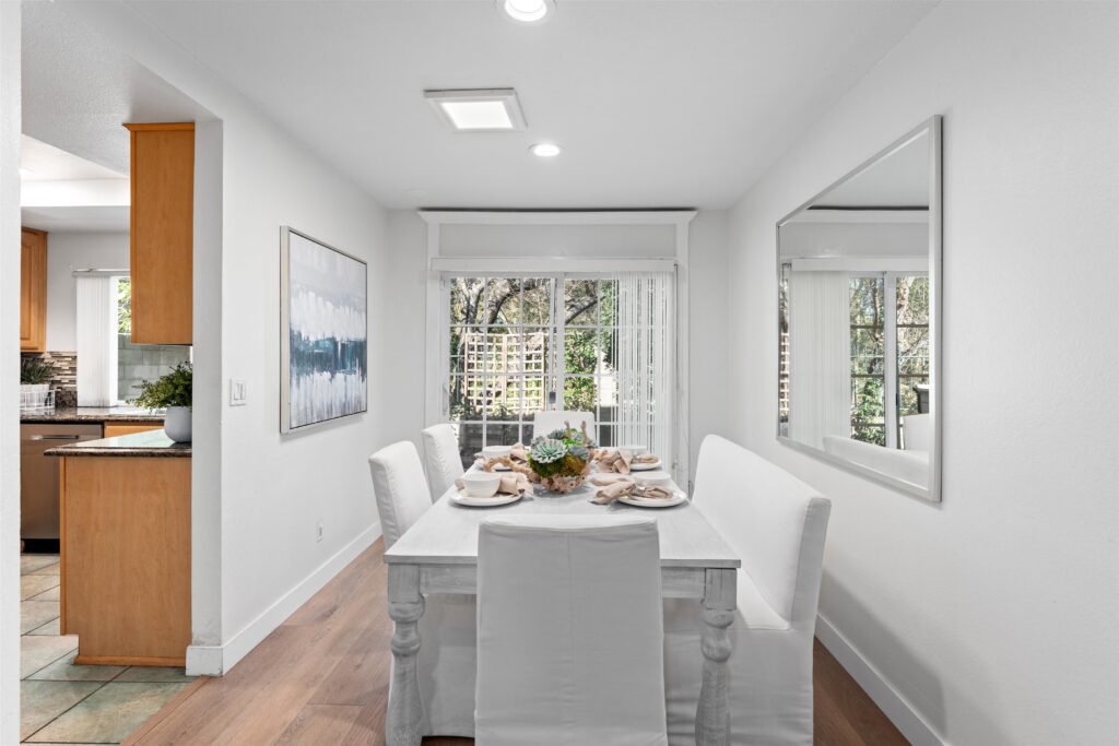 Cost of Home Staging Services: Is Professional Staging Worth the Investment? 3 A dining room featuring a white table surrounded by white chairs, creating a clean and modern aesthetic.