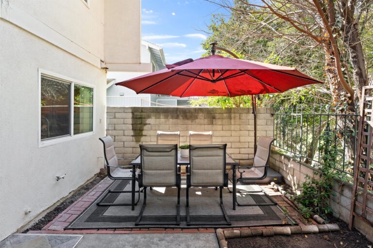 A charming patio displaying a table and chairs under an umbrella, perfect for enjoying meals in the fresh air.